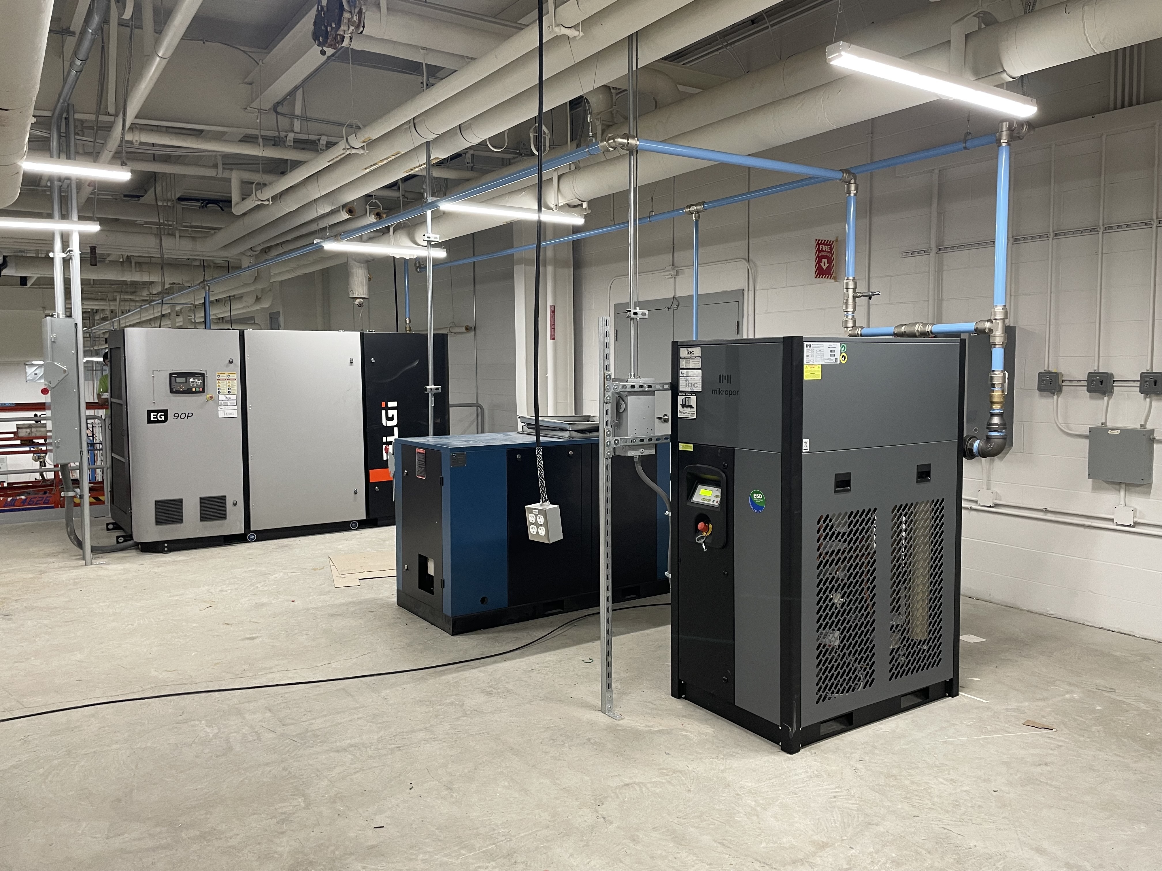 A clean, organized compressor room featuring ELGi and Mikropor equipment. This system represents IAC’s Compressed Air as a Utility (CAS) model, delivering a continuous, monitored air supply managed entirely by IAC.